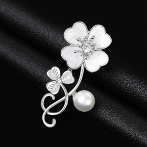 Detailed view of silver clover brooch with white shell petals and large pearl pendant