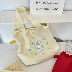 Close-up of cute rabbit embroidery on a cream nylon drawstring tote bag surface