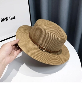 Close-up of summer straw boater hat featuring a brown leather band and gold buckle