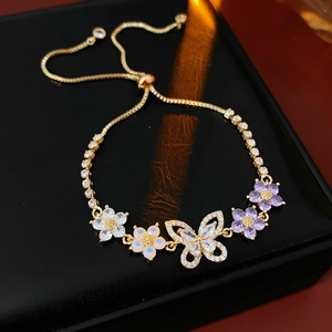 Nahaufnahme des goldenen Schmetterlingsarmbands mit Zirkonia und Opalblüten auf Leder