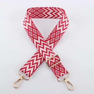 Detail of red and white geometric embroidery on adjustable strap with gold metal hooks