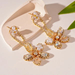 Detailed shot of gold tassel earrings with pearls and crystals on stone background