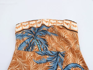 Detail of tropical palm tree print on orange strapless dress with wavy top edge