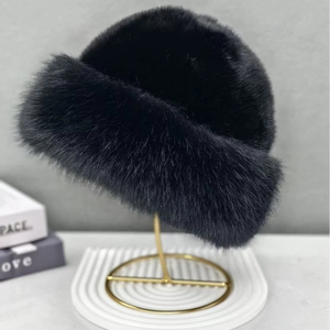 Detail of a plush black faux fur bucket hat displayed on a gold stand for winter warmth