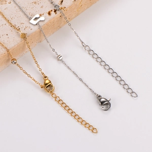 Detailed view of gold and silver anklets with music note and H letter charms on stone