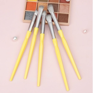 Five yellow diamond-cut eye makeup brushes with soft bristles on a pink background