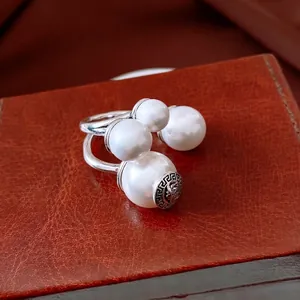 Vintage style silver ring with four white pearls and lion head relief on a leather surface