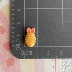 Miniatur Spirale aus gelb-rosa Kunstharz auf einer Skalmatte zur Größenbestimmung gezeigt