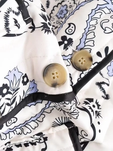 Detail of paisley quilted fabric with marble buttons and black satin piping on the coat