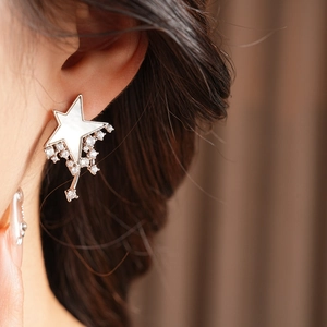 Detail of star-shaped stud earring with white shell inlay and zircon dangles