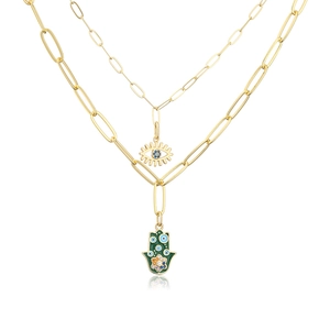 Close-up of double-layer gold Hamsa Hand and Evil Eye pendants with green enamel