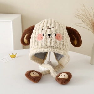 Close-up of knit dog hat with plush brown ears, embroidery detail, and pom-poms