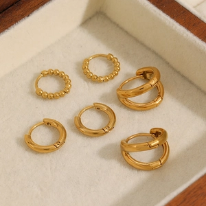 Lot de trois paires de boucles d'oreilles créoles en acier doré dans un coffret en bois
