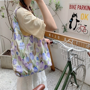 Dettaglio della borsa tote grande in tela floreale con motivi di tulipani portata da modella