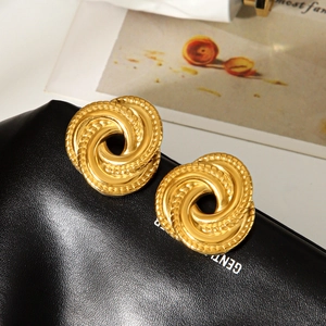 Boucles d'oreilles créoles torsadées dorées vintage en acier sur texture cuir noir