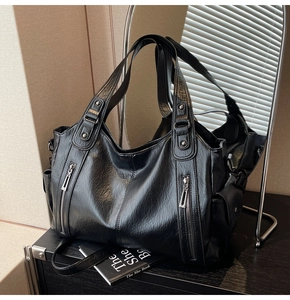 Detailed front view of black vintage leather tote bag with side zipper pockets and double handles