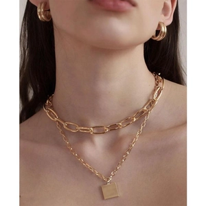 Close-up of a layered gold chunky chain necklace with a square pendant and hoop earrings