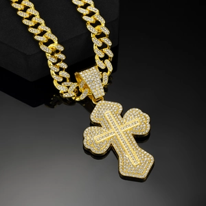 Detail of iced out gold cuban chain necklace with diamond cross pendant on black podium