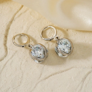 Elegant geometric silver earrings with round cubic zirconia on beige silk background