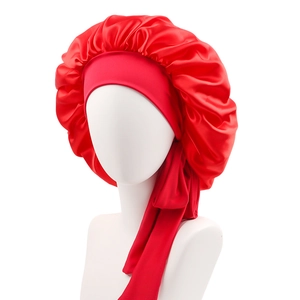Detail of red satin sleep bonnet with long stretchy ribbons on a white mannequin head
