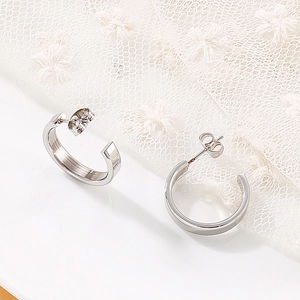 Detailed macro view of polished stainless steel C-shaped earrings on lace background