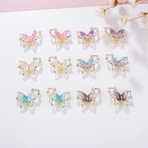 Detailed grid showing twelve colorful 3D butterfly nail charms with pearls and aurora stones