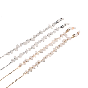 Close-up of four stylish gold and silver glasses chains with white natural stone accents