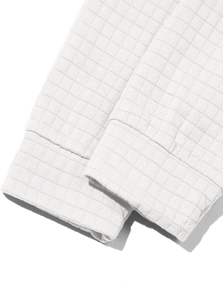 Close-up of white waffle knit fabric texture and cuff stitching on men's pullover
