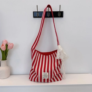 Detail of red striped canvas bag with elegant white lace bow hanging on a hook