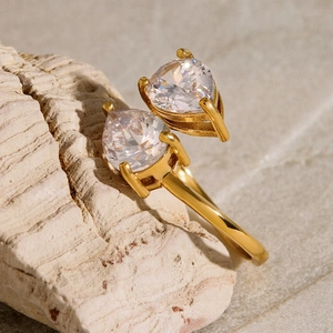 Detail of gold-plated open ring featuring two teardrop-shaped zircons on a rock surface