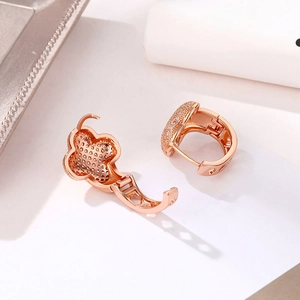 Close-up of 18K rose gold four-leaf clover hoop earrings with shimmering white zircon stones