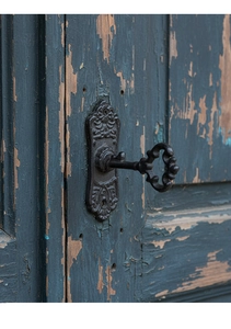 Gros plan sur une clé en fonte vintage et sa plaque ornée sur une porte en bois rustique
