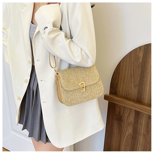 Detailed view of woven crossbody bag with gold U-shaped buckle and textured straw finish