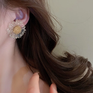 Detailed view of a transparent flower earring with golden core on a model's ear