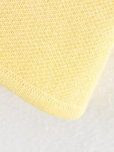 Vue macro de la texture du tricot jaune avec couture de bordure surjetée précise