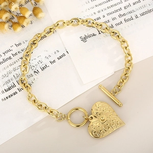 Punk style golden heart pendant bracelet with OT clasp and embossed patterns on a book