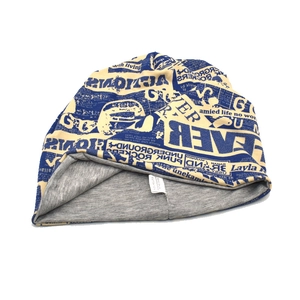 Detail view of cotton beanie with vintage newspaper print and interior gray lining