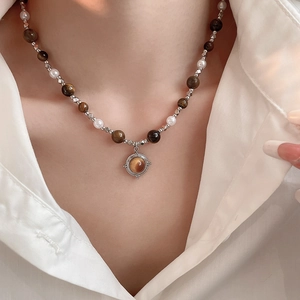 Close-up of beaded necklace with tiger eye stone and pearls worn on a white shirt