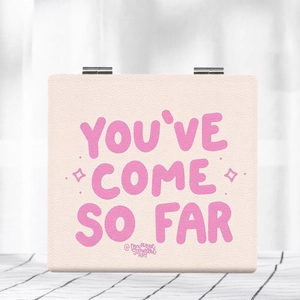 Macro view of pink faux leather foldable mirror with YOU'VE COME SO FAR quote detail