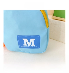 Détail de la texture en nylon bleu et de la fermeture éclair jaune du sac bandoulière enfant