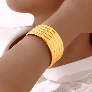Modern layered stainless steel open cuff bracelet in gold finish worn on wrist