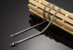 Detailed close-up of a silver stainless steel woven chain necklace with a lobster clasp