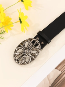 Detail of a black leather belt featuring a vintage silver floral engraved buckle
