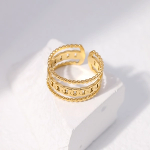 Detailed view of adjustable multi-layer gold chain ring on white textured stone pedestal