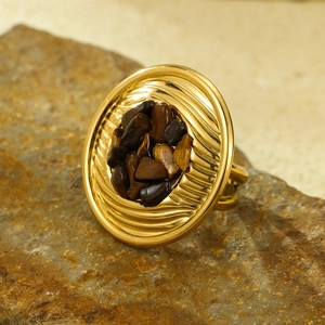 Detail of gold circular ring with brown stone inlay on a natural stone surface