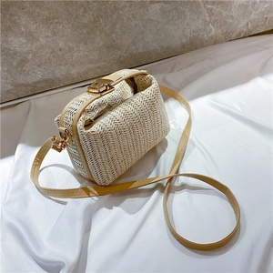 Minimalist beige woven crossbody straw bag with gold buckle on white satin background