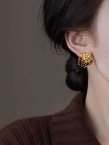 Close-up of vintage gold tassel earrings with brown stones and sparkling zircons on model