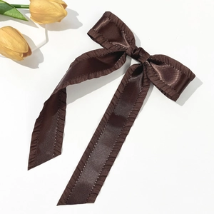 Close-up of a coffee brown satin bow hair clip with ruffled edges and long streamers