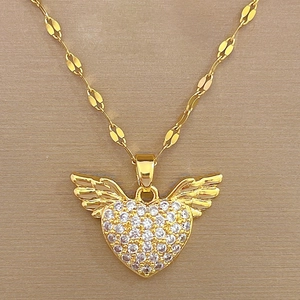 Detailed macro of golden heart pendant with angel wings and diamond inlay on textured fabric