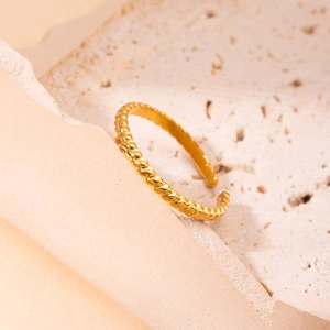 Elegant gold twisted rope open ring made of titanium steel displayed on a stone surface
